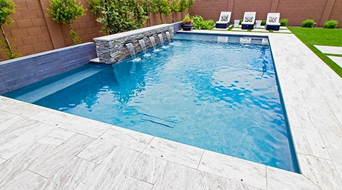 Compact rectangular pool with sheer descent water features in a walled backyard